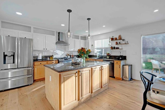 kitchen featuring light hardwood / wood-style flooring, wall chimney range hood, stainless steel appliances, and a kitchen island