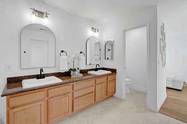 bathroom with toilet, tile patterned floors, and vanity