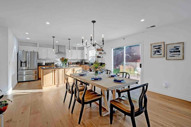 dining space featuring a notable chandelier, sink, and light hardwood / wood-style floors