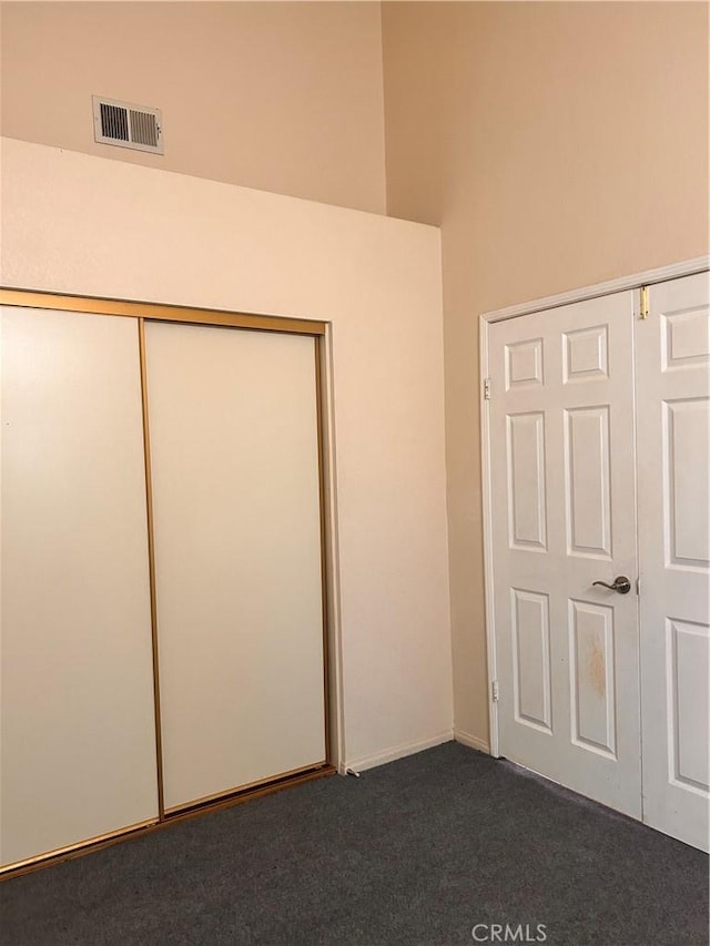 unfurnished bedroom featuring a closet and dark carpet