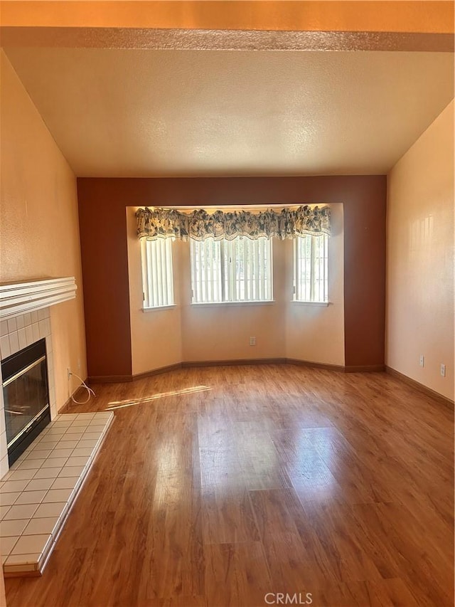 unfurnished living room with wood-type flooring, a textured ceiling, and a fireplace