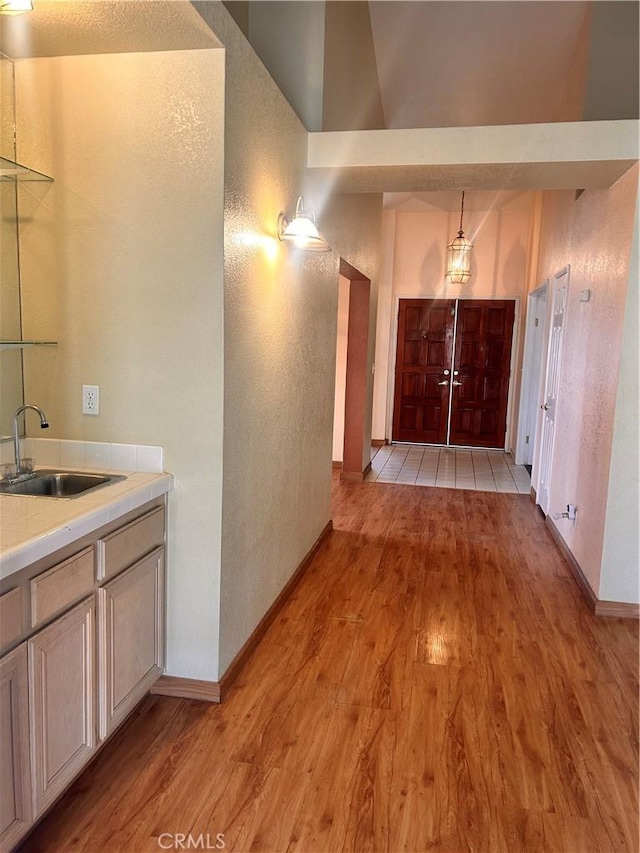 hall featuring lofted ceiling, light hardwood / wood-style flooring, and sink