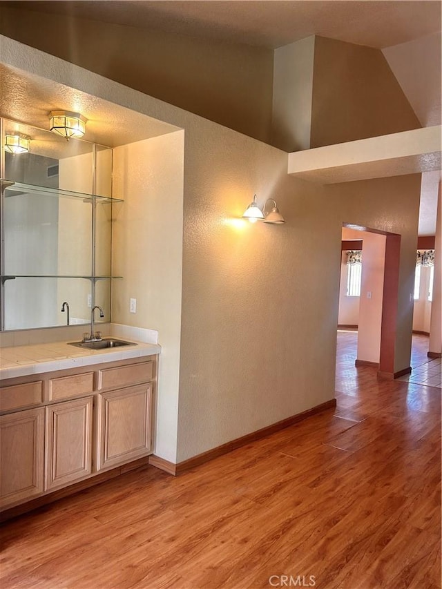 interior space with light brown cabinetry, light hardwood / wood-style floors, a high ceiling, and sink