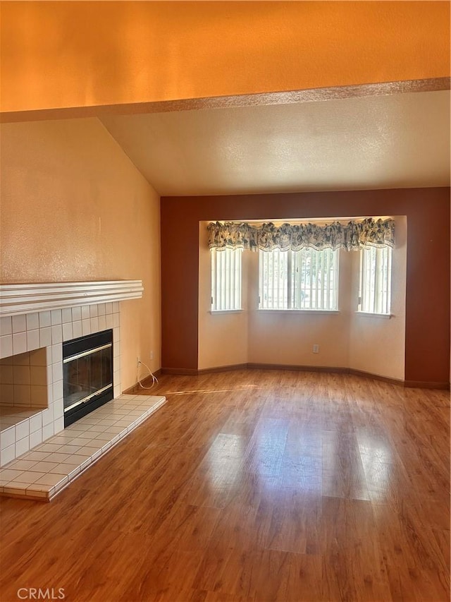 unfurnished living room with a tiled fireplace and light hardwood / wood-style flooring