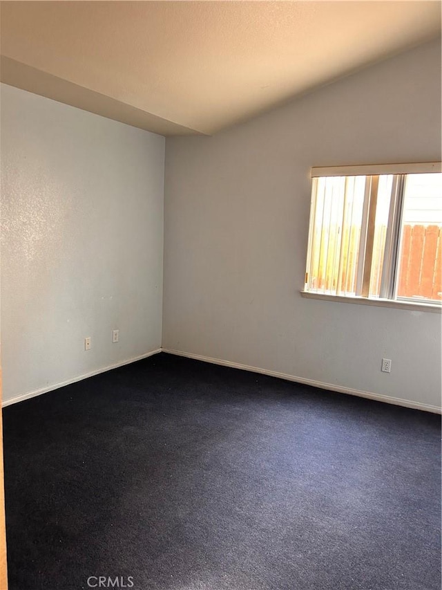 carpeted empty room featuring lofted ceiling