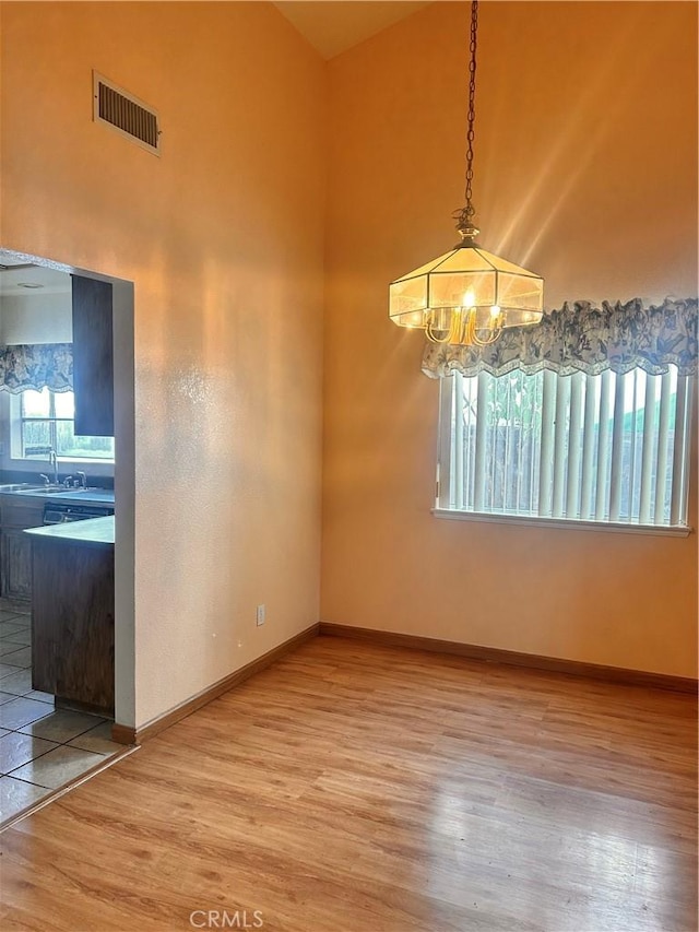 unfurnished dining area featuring a notable chandelier, sink, and hardwood / wood-style floors