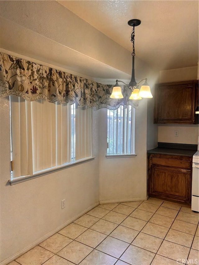 unfurnished dining area with an inviting chandelier and light tile patterned flooring