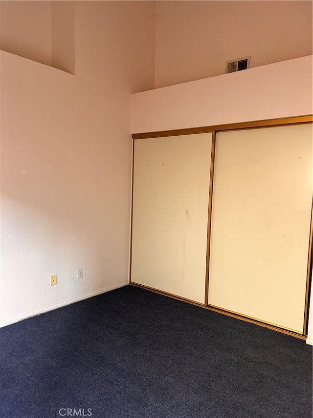 unfurnished bedroom featuring carpet, a closet, and a high ceiling