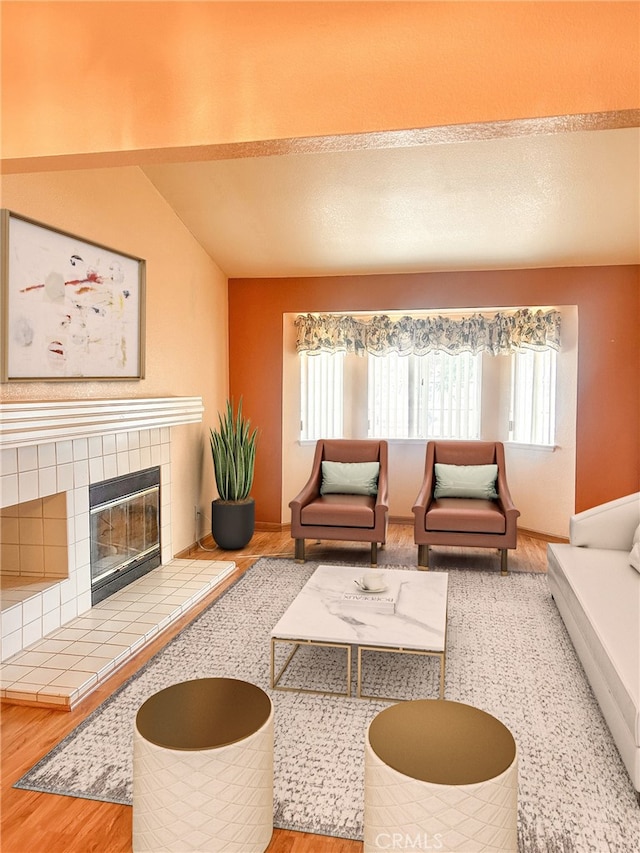 living room with hardwood / wood-style flooring, a wealth of natural light, a tiled fireplace, and vaulted ceiling