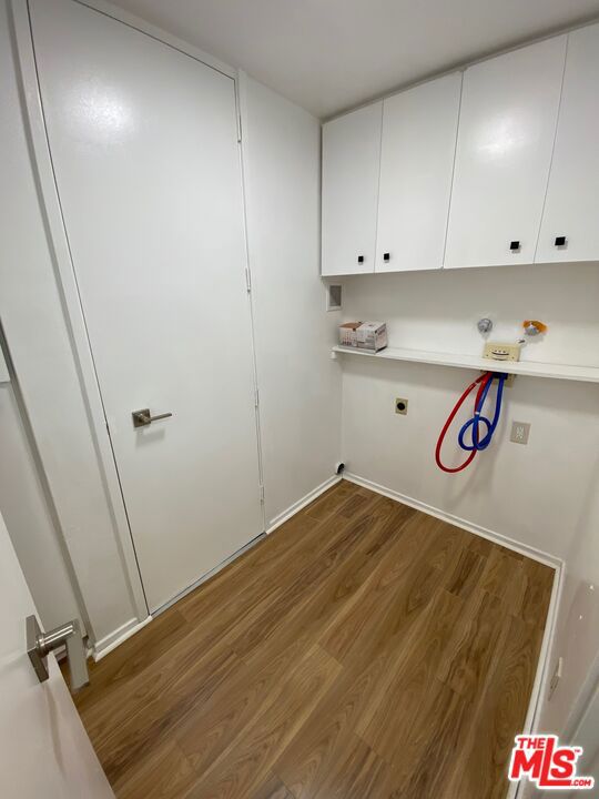 clothes washing area featuring dark wood-type flooring, cabinets, and electric dryer hookup