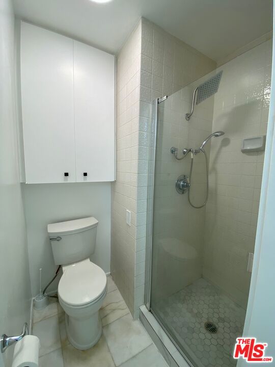 bathroom with toilet and a shower with door