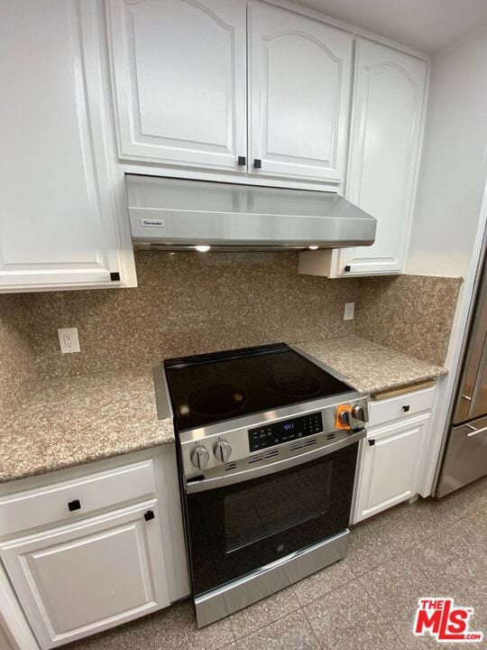 kitchen featuring decorative backsplash, light stone countertops, white cabinetry, and high end stainless steel range oven