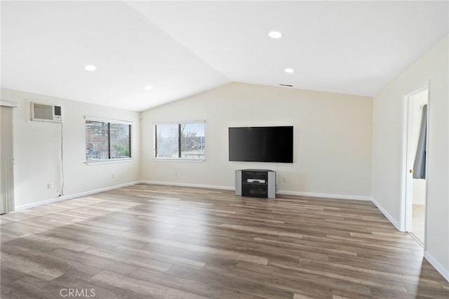 unfurnished living room with lofted ceiling, hardwood / wood-style flooring, and a wall mounted air conditioner