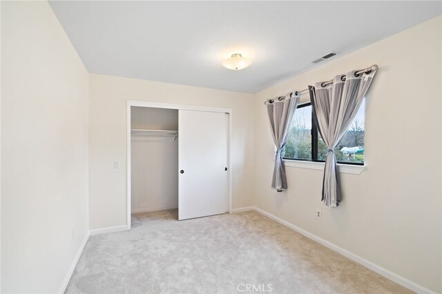 unfurnished bedroom featuring a closet and light colored carpet