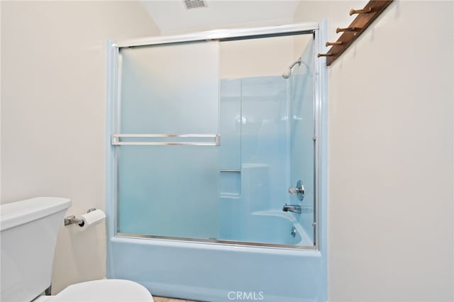 bathroom with toilet and bath / shower combo with glass door