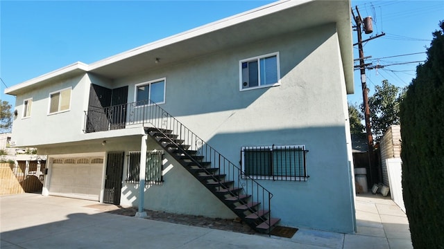 exterior space with driveway, stairway, fence, and stucco siding