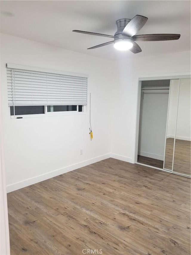 unfurnished bedroom featuring a closet, ceiling fan, baseboards, and wood finished floors