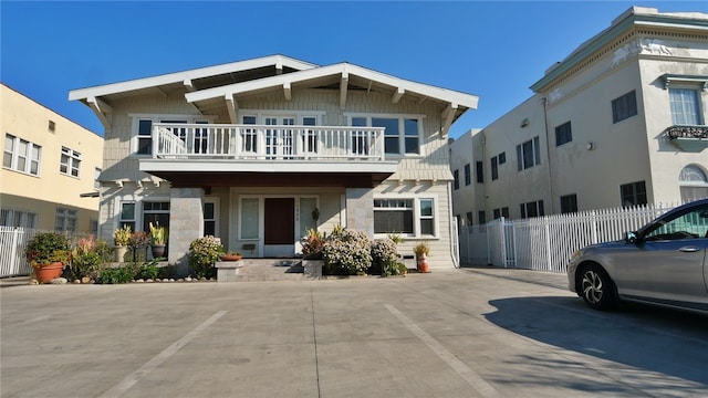 townhome / multi-family property featuring a balcony, uncovered parking, and fence