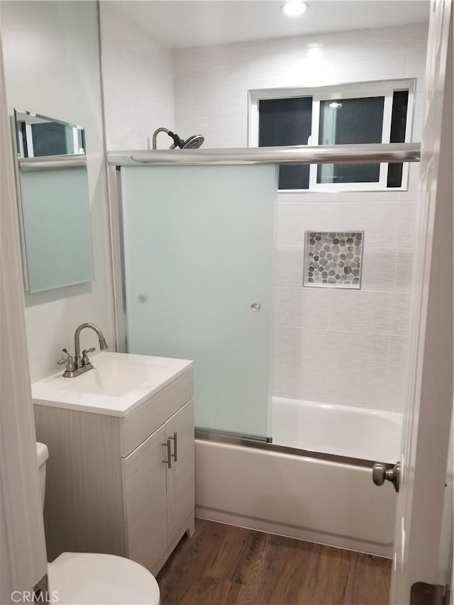 full bath with bath / shower combo with glass door, vanity, toilet, and wood finished floors