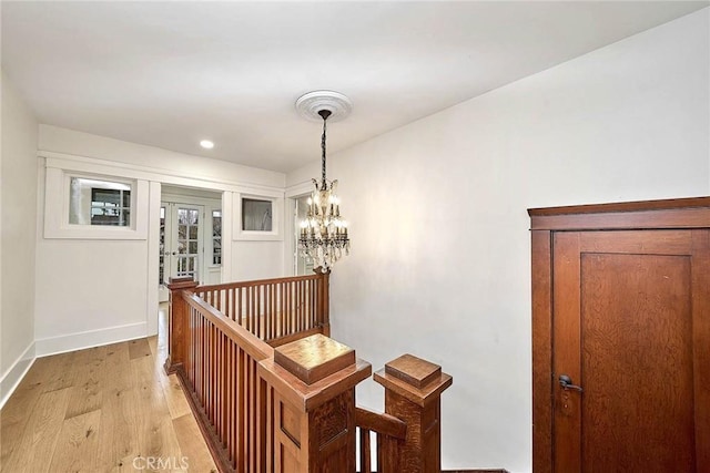 hallway with baseboards, an upstairs landing, light wood-style floors, a notable chandelier, and recessed lighting