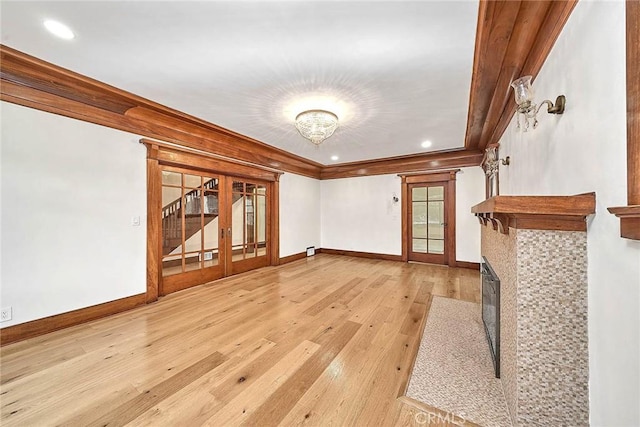 unfurnished living room featuring crown molding, wood-type flooring, a fireplace with flush hearth, and baseboards