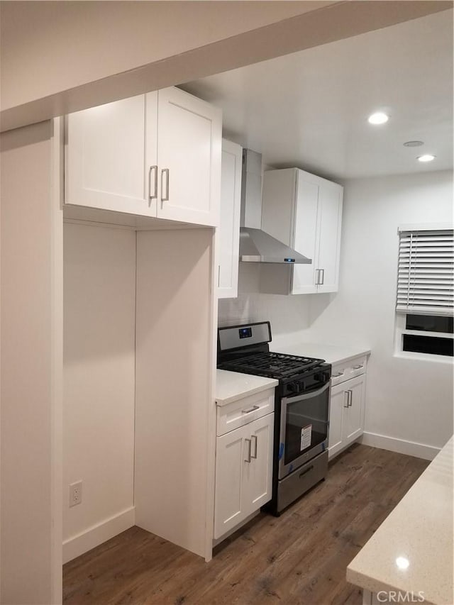 kitchen featuring dark wood-style floors, wall chimney exhaust hood, gas range, and white cabinets