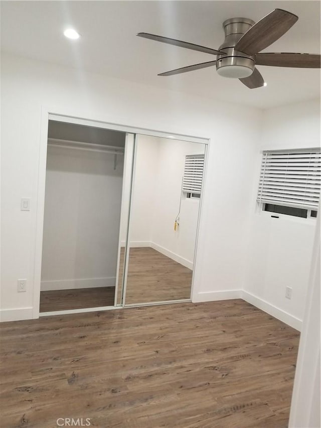 unfurnished bedroom featuring a closet, baseboards, wood finished floors, and recessed lighting