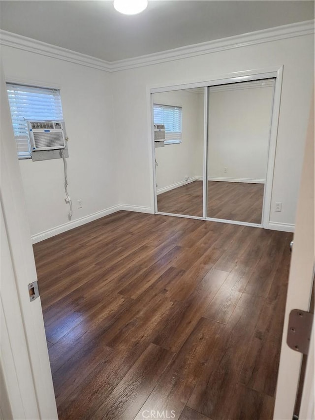 unfurnished bedroom with baseboards, a closet, wood finished floors, and crown molding