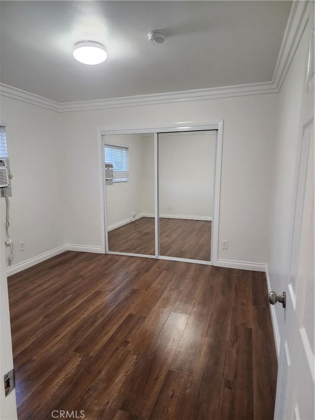 unfurnished bedroom featuring baseboards, a closet, wood finished floors, and crown molding