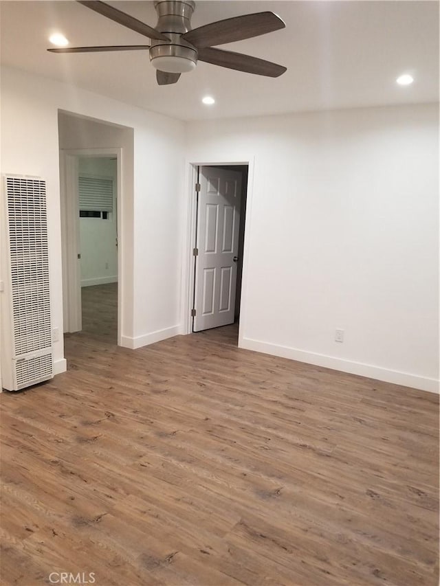 unfurnished room with a ceiling fan, recessed lighting, a heating unit, and wood finished floors