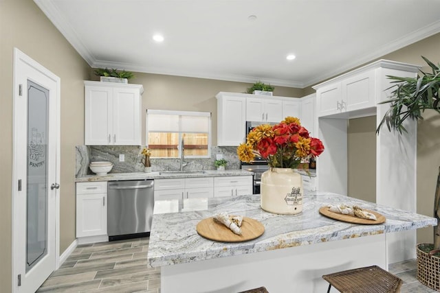 kitchen featuring backsplash, stainless steel dishwasher, sink, white cabinetry, and ornamental molding