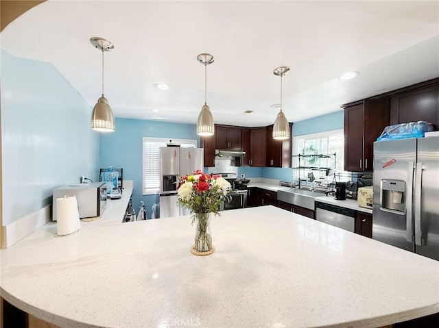 kitchen with stainless steel appliances, pendant lighting, dark brown cabinets, and sink