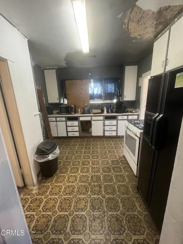 kitchen with black refrigerator with ice dispenser, white range with gas cooktop, and white cabinetry