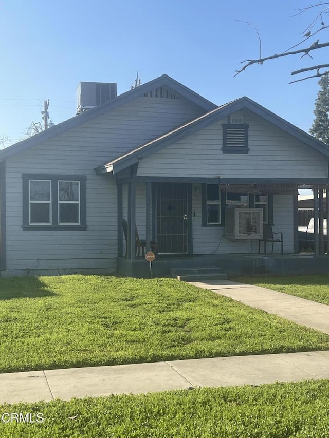 view of front of property featuring central AC unit, covered porch, and a front lawn