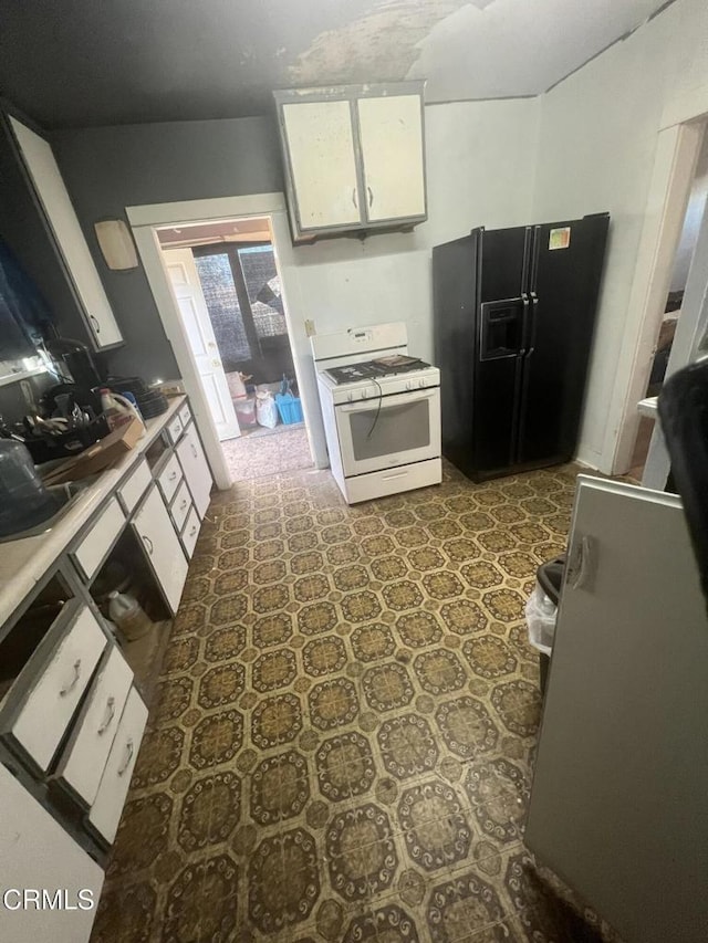 kitchen with white cabinets, black refrigerator with ice dispenser, and white gas stove