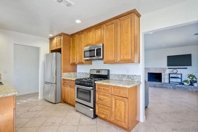 kitchen with light stone countertops, light tile patterned floors, and stainless steel appliances