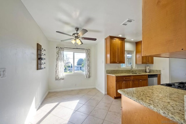 kitchen with ceiling fan, stainless steel dishwasher, sink, light tile patterned flooring, and light stone countertops