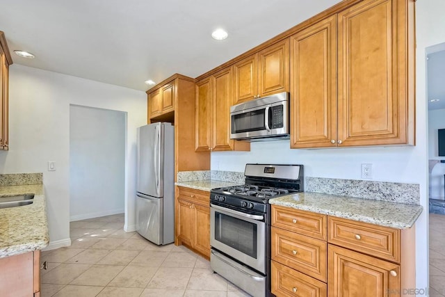 kitchen featuring light tile patterned floors, appliances with stainless steel finishes, sink, and light stone countertops