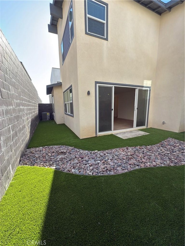 back of house featuring central AC and a lawn