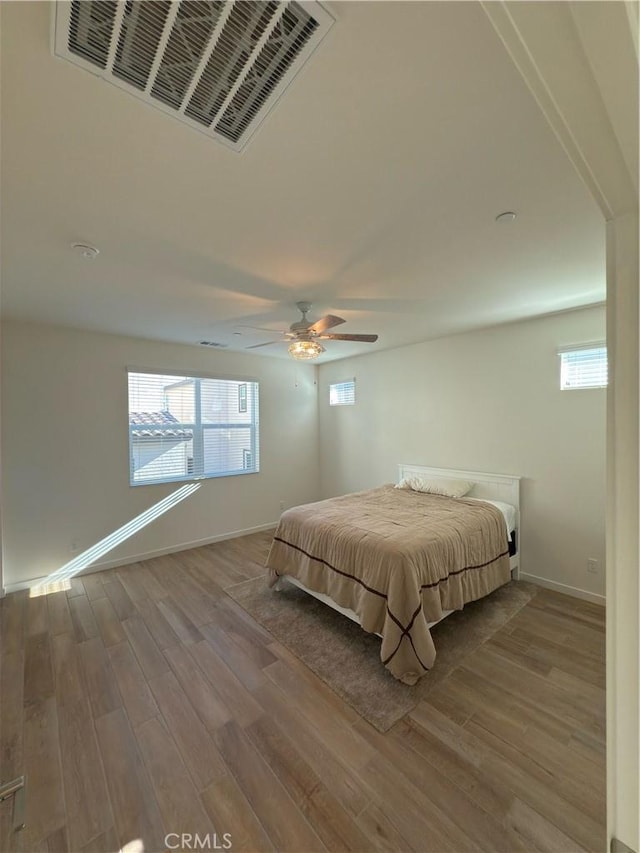 unfurnished bedroom with ceiling fan, light hardwood / wood-style flooring, and multiple windows