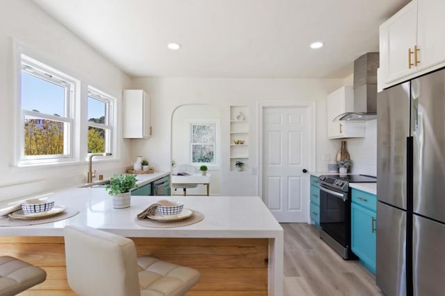 kitchen featuring a breakfast bar, white cabinetry, stainless steel appliances, blue cabinets, and wall chimney exhaust hood