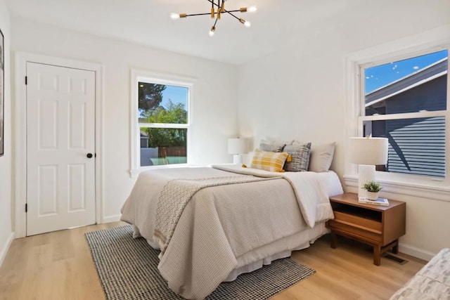 bedroom with a chandelier and light hardwood / wood-style floors