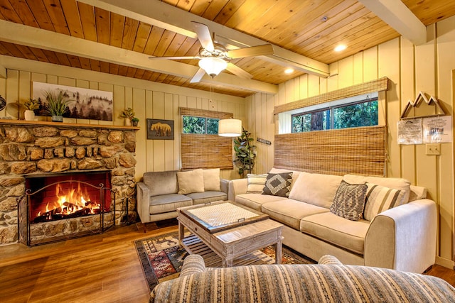 living room featuring beam ceiling, a fireplace, wood walls, and hardwood / wood-style flooring