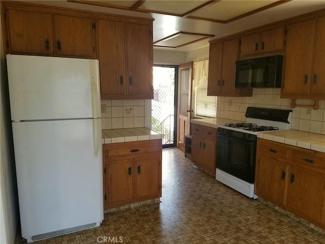 kitchen featuring backsplash, white appliances, and tile counters