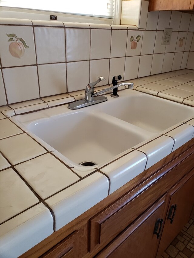 interior details with decorative backsplash, sink, and tile countertops