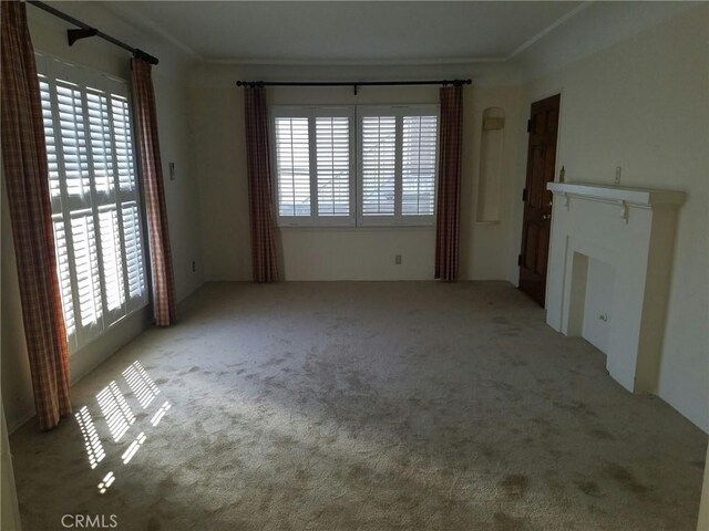 unfurnished living room with ornamental molding and light carpet