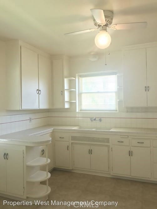 kitchen with tasteful backsplash, white cabinets, ceiling fan, and sink