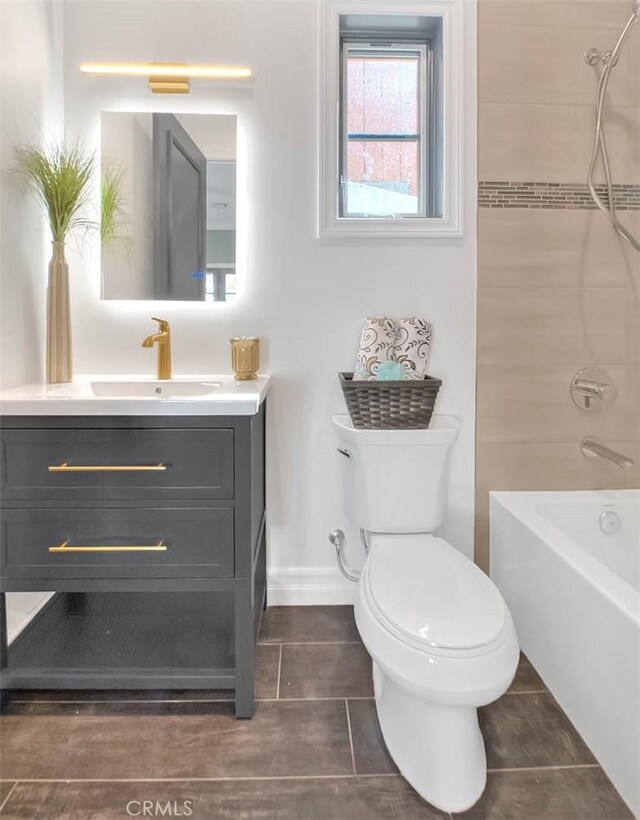 full bathroom featuring toilet, vanity, tiled shower / bath, and tile patterned flooring