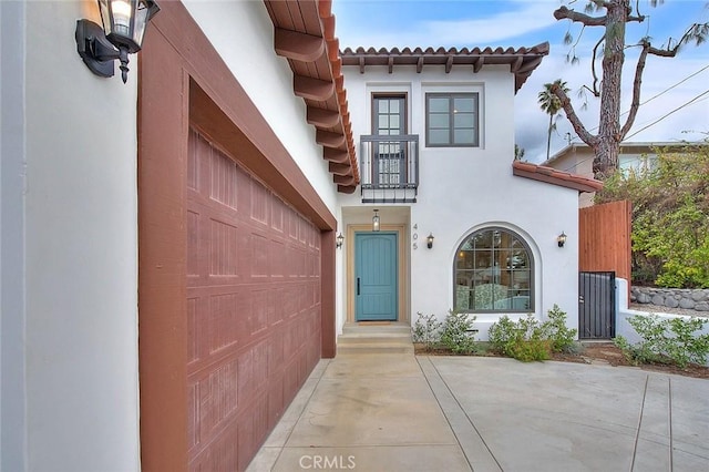 view of exterior entry featuring a garage and a balcony