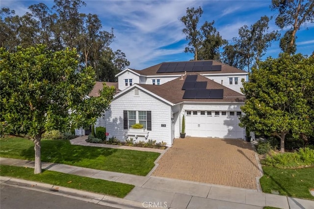 view of front of home featuring a front lawn, solar panels, and a garage